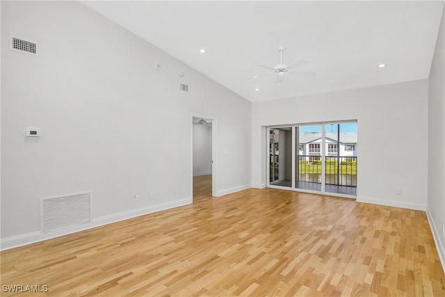 empty room with ceiling fan, a high ceiling, and light wood-type flooring