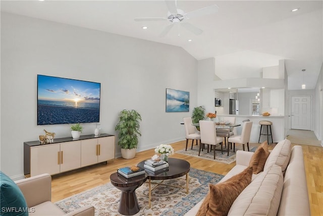 living room featuring ceiling fan, lofted ceiling, and light wood-type flooring