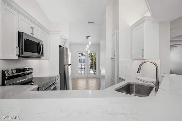 kitchen with sink, french doors, light stone counters, white cabinets, and appliances with stainless steel finishes