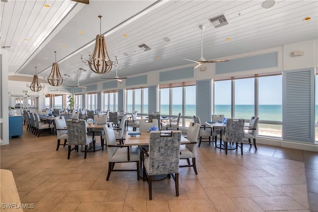 dining room featuring ceiling fan with notable chandelier, a water view, and wood ceiling