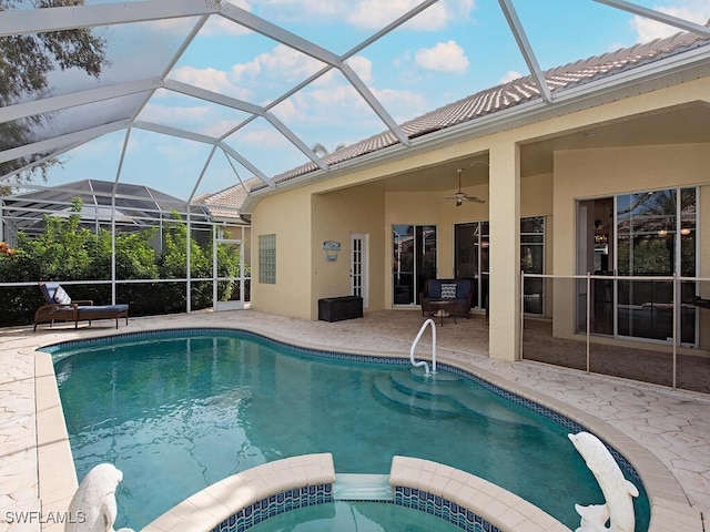 view of pool featuring glass enclosure, ceiling fan, a patio, and an in ground hot tub