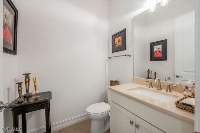 bathroom featuring toilet, baseboards, and vanity