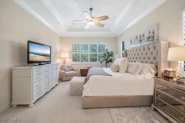 bedroom with ornamental molding, a tray ceiling, light carpet, and a ceiling fan