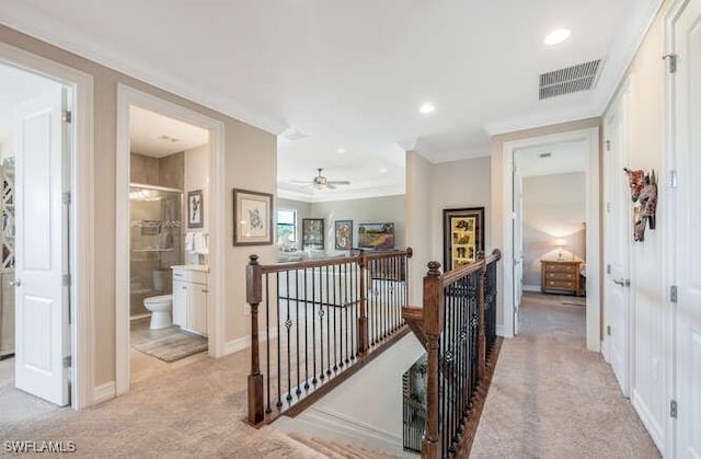 hall featuring visible vents, light carpet, an upstairs landing, and crown molding