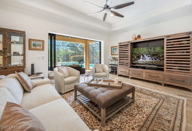 living area with a ceiling fan, a sunroom, and a raised ceiling