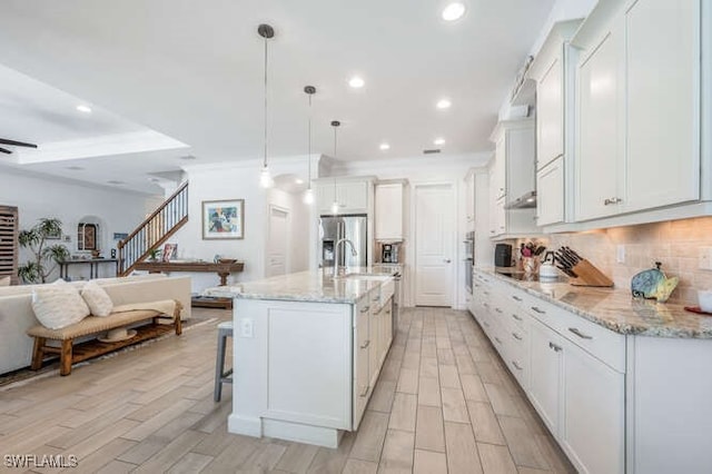kitchen with tasteful backsplash, recessed lighting, open floor plan, white cabinetry, and stainless steel fridge with ice dispenser