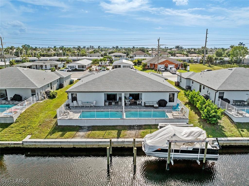 back of property featuring a lawn, a patio area, and a water view