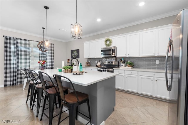 kitchen with a kitchen bar, stainless steel appliances, a kitchen island with sink, white cabinetry, and hanging light fixtures