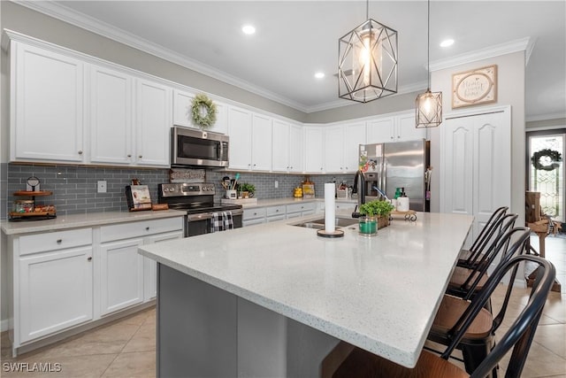 kitchen with pendant lighting, a kitchen island with sink, white cabinets, a kitchen breakfast bar, and stainless steel appliances