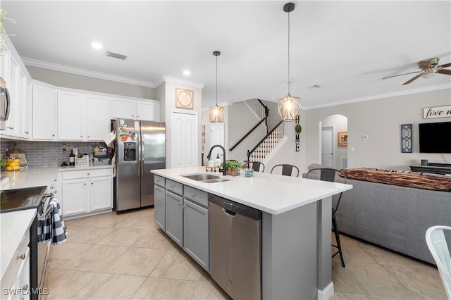 kitchen with appliances with stainless steel finishes, a kitchen breakfast bar, sink, white cabinets, and an island with sink