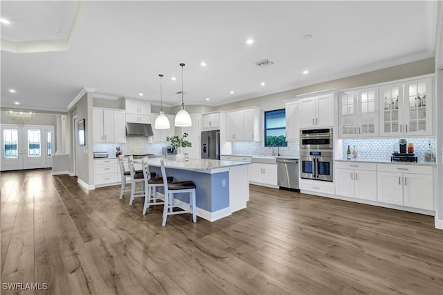 kitchen featuring white cabinetry, appliances with stainless steel finishes, dark wood-type flooring, hanging light fixtures, and a kitchen island