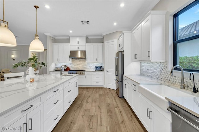 kitchen featuring hanging light fixtures, white cabinets, light stone countertops, and appliances with stainless steel finishes