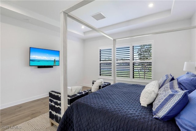 bedroom with wood-type flooring and a tray ceiling