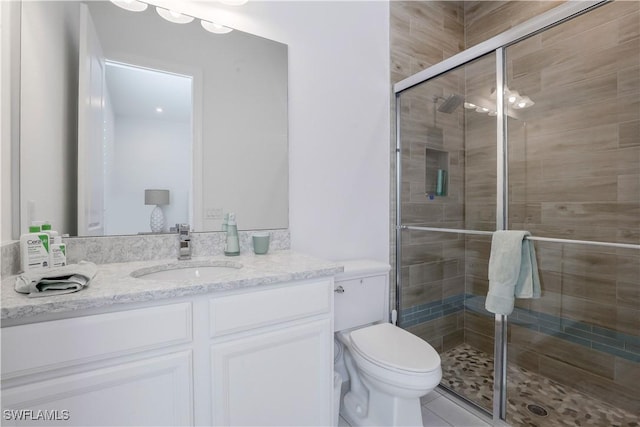 bathroom featuring toilet, a shower with door, and vanity