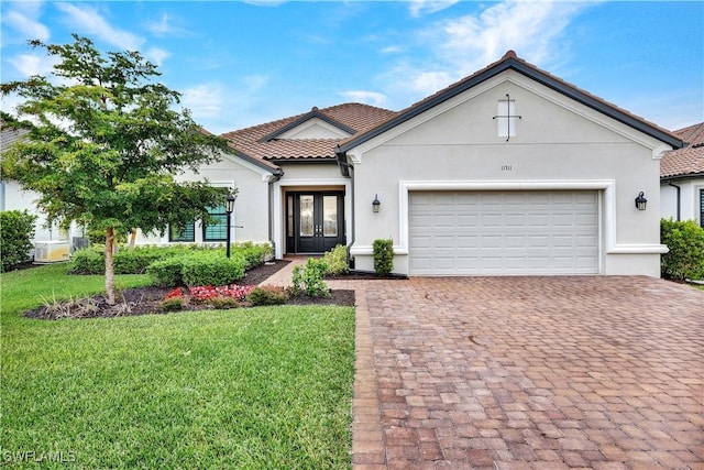 view of front of house featuring a front lawn, a garage, and french doors