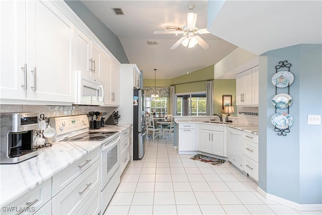 kitchen featuring tasteful backsplash, lofted ceiling, sink, white appliances, and white cabinets