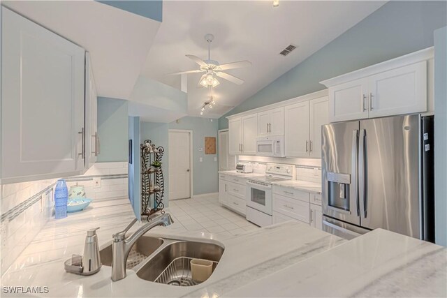 kitchen with lofted ceiling, tasteful backsplash, white appliances, and white cabinetry