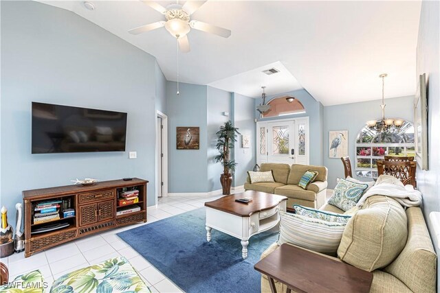 tiled living room with ceiling fan with notable chandelier and vaulted ceiling