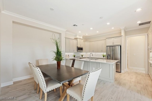 dining area featuring crown molding, sink, and light hardwood / wood-style floors