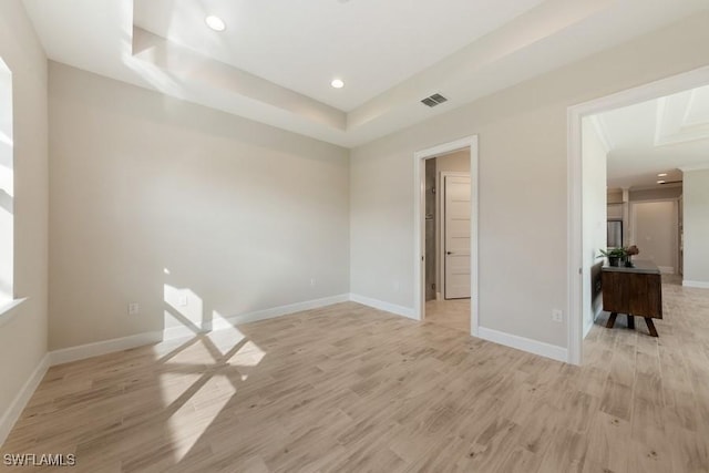 unfurnished room featuring a raised ceiling and light hardwood / wood-style flooring