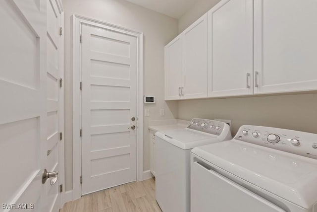 laundry room featuring light hardwood / wood-style flooring, cabinets, and independent washer and dryer