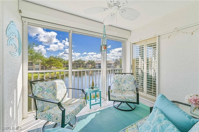 sunroom featuring ceiling fan and a water view