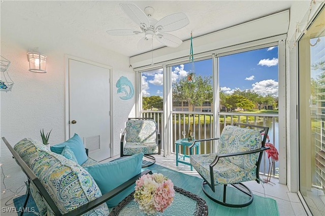 sunroom with ceiling fan and a water view