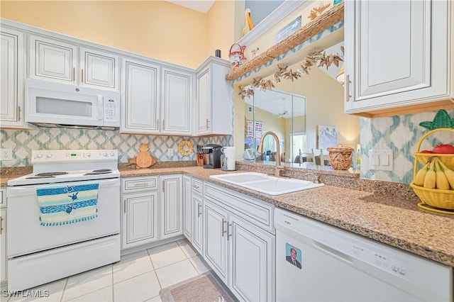 kitchen with sink, tasteful backsplash, light tile patterned flooring, white appliances, and white cabinets