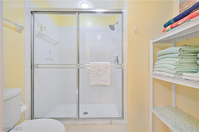 bathroom featuring toilet and a shower with shower door