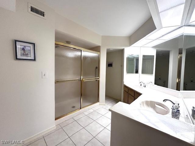 bathroom featuring tile patterned flooring, vanity, and a shower with shower door