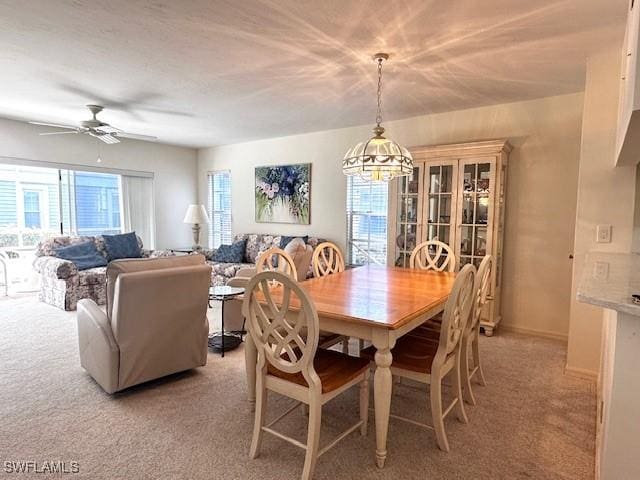 dining space featuring light carpet and ceiling fan