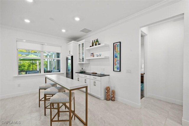 kitchen with stainless steel refrigerator, crown molding, white cabinets, and light tile patterned floors