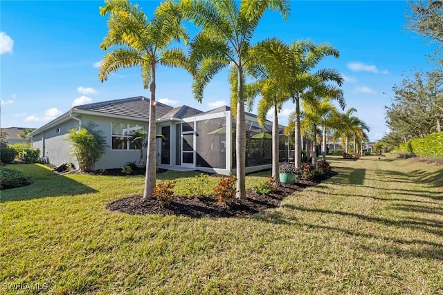 rear view of house with a lanai and a lawn