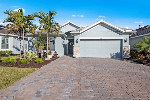 single story home featuring decorative driveway, an attached garage, and stucco siding