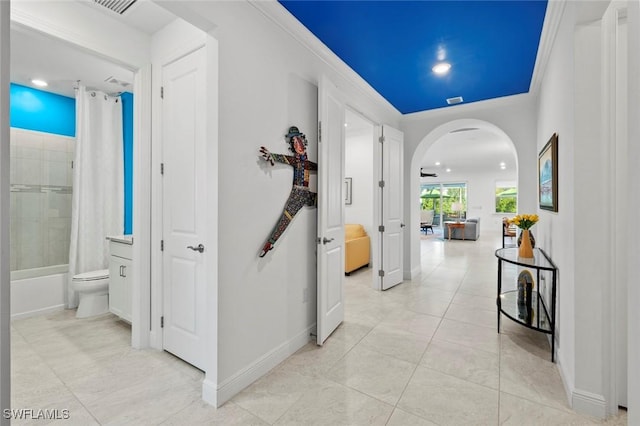 hallway with crown molding and light tile patterned flooring