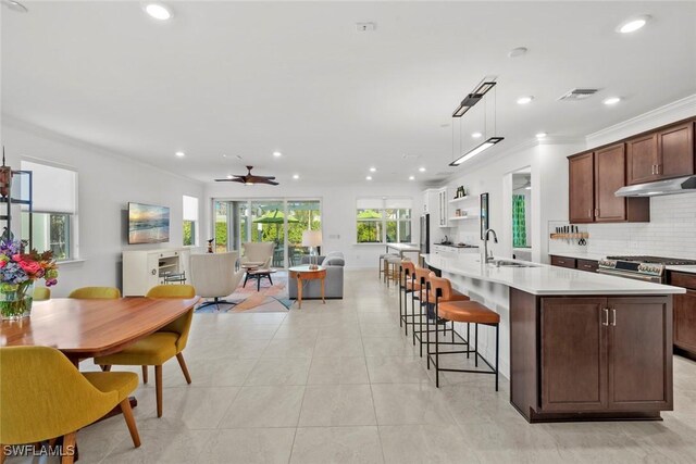 kitchen featuring ceiling fan, sink, tasteful backsplash, decorative light fixtures, and a kitchen island with sink