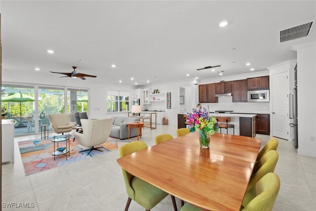 dining space featuring ceiling fan, light tile patterned flooring, and ornamental molding