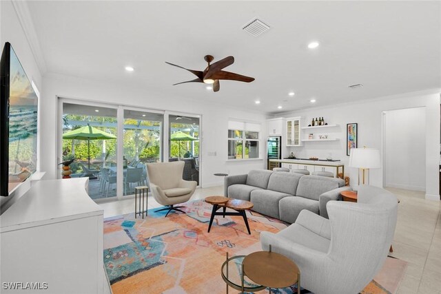 tiled living room with ceiling fan and ornamental molding