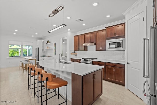 kitchen featuring sink, hanging light fixtures, backsplash, an island with sink, and appliances with stainless steel finishes