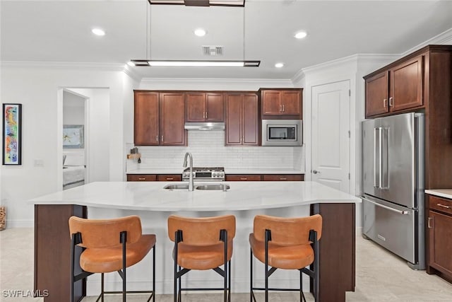 kitchen featuring appliances with stainless steel finishes, a center island with sink, crown molding, and sink