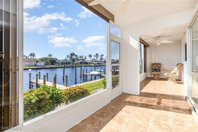 sunroom with ceiling fan and a water view