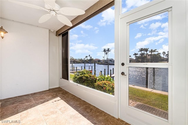 sunroom featuring ceiling fan and a water view