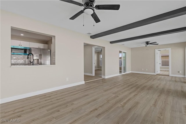 unfurnished living room featuring beam ceiling, light wood-type flooring, and ceiling fan