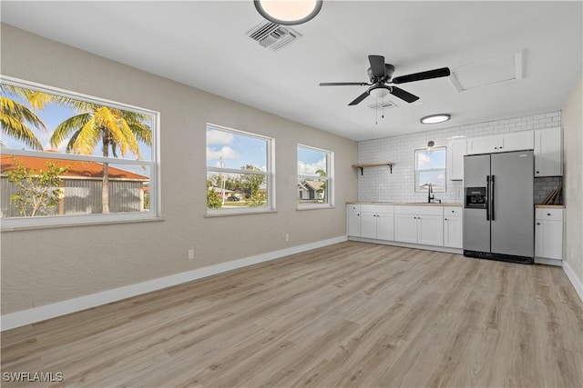 kitchen with decorative backsplash, light wood-type flooring, sink, stainless steel fridge with ice dispenser, and white cabinetry