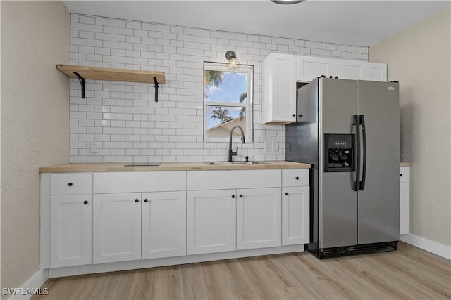 kitchen featuring white cabinets, stainless steel fridge, sink, and wooden counters