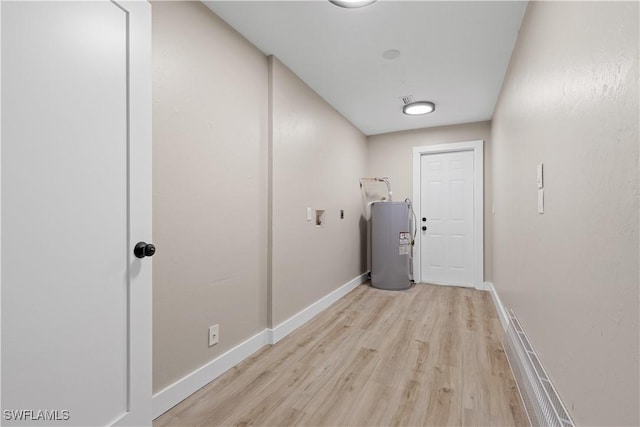 laundry area featuring electric water heater and light hardwood / wood-style flooring