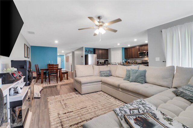 living room with ceiling fan and light hardwood / wood-style flooring