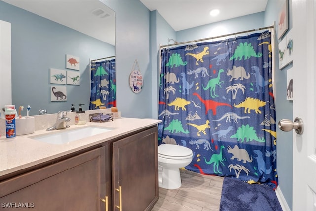 bathroom featuring walk in shower, hardwood / wood-style floors, vanity, and toilet