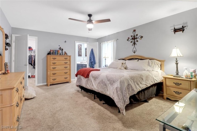 bedroom featuring ensuite bath, ceiling fan, a walk in closet, light carpet, and a closet