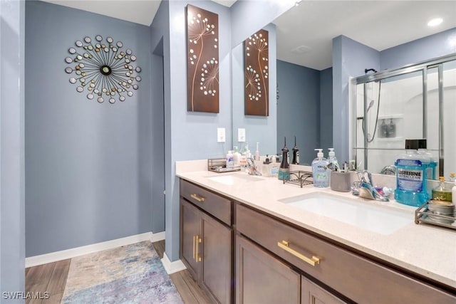 bathroom with hardwood / wood-style floors, vanity, and a shower with door